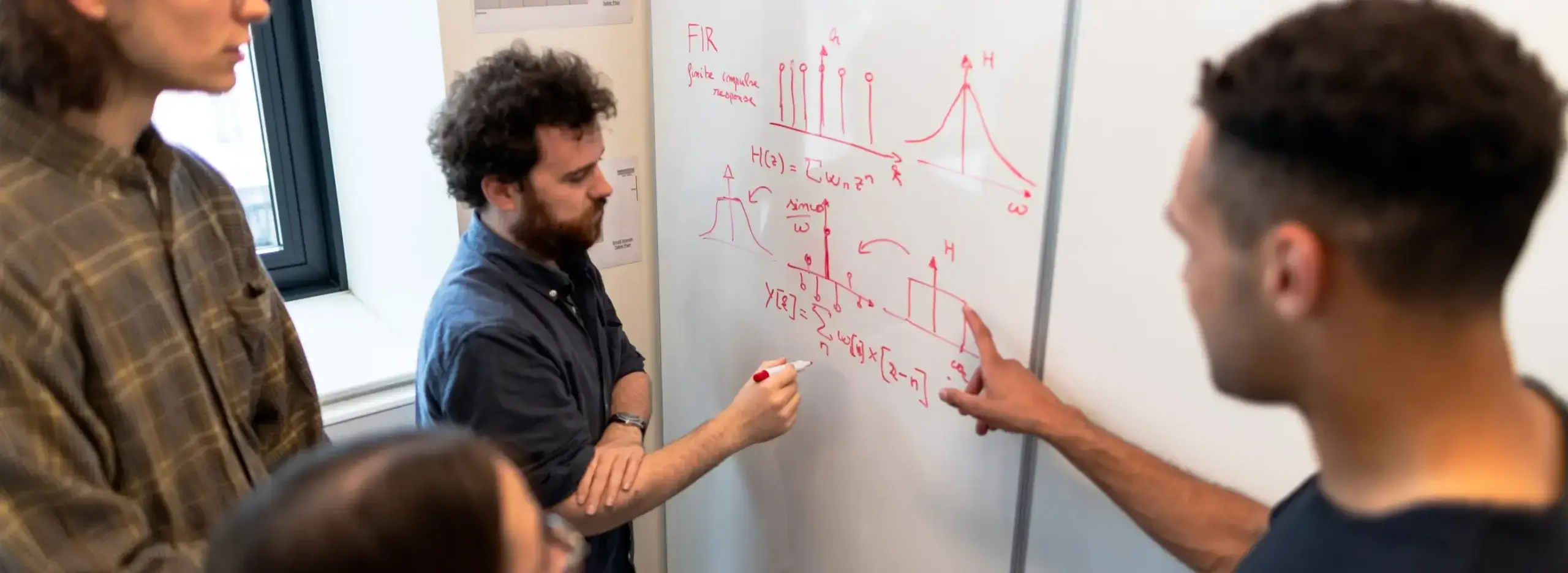 Product development ideas on a whiteboard with a few people around the white board talking